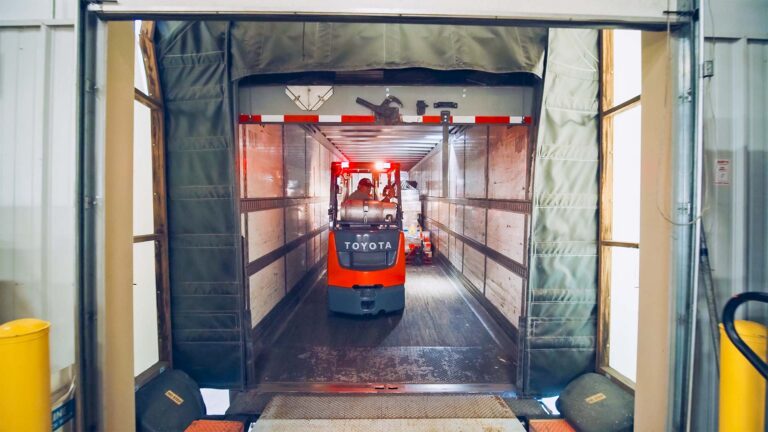 A forklift operator moving palletized materials off an inbound truck