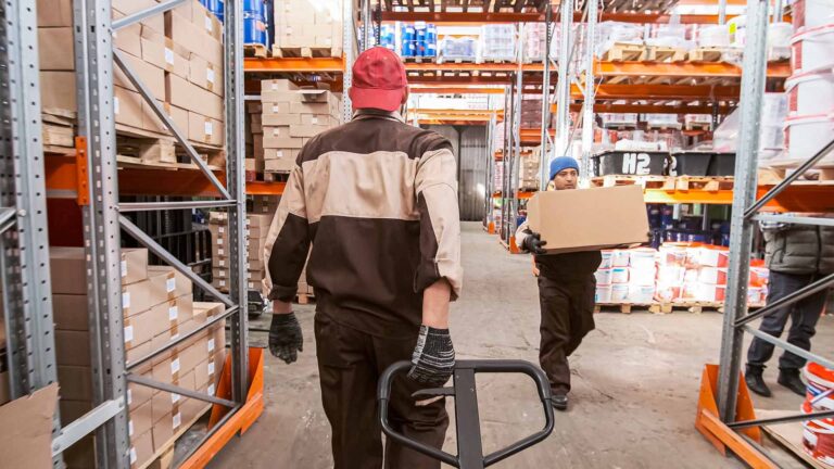 Warehouse workers moving material on dollies and hand carrying boxes