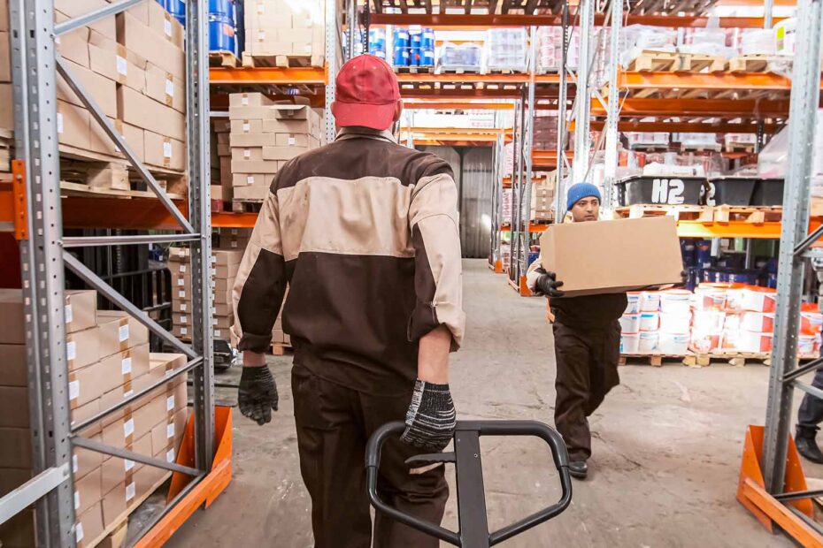 Warehouse workers moving material on dollies and hand carrying boxes