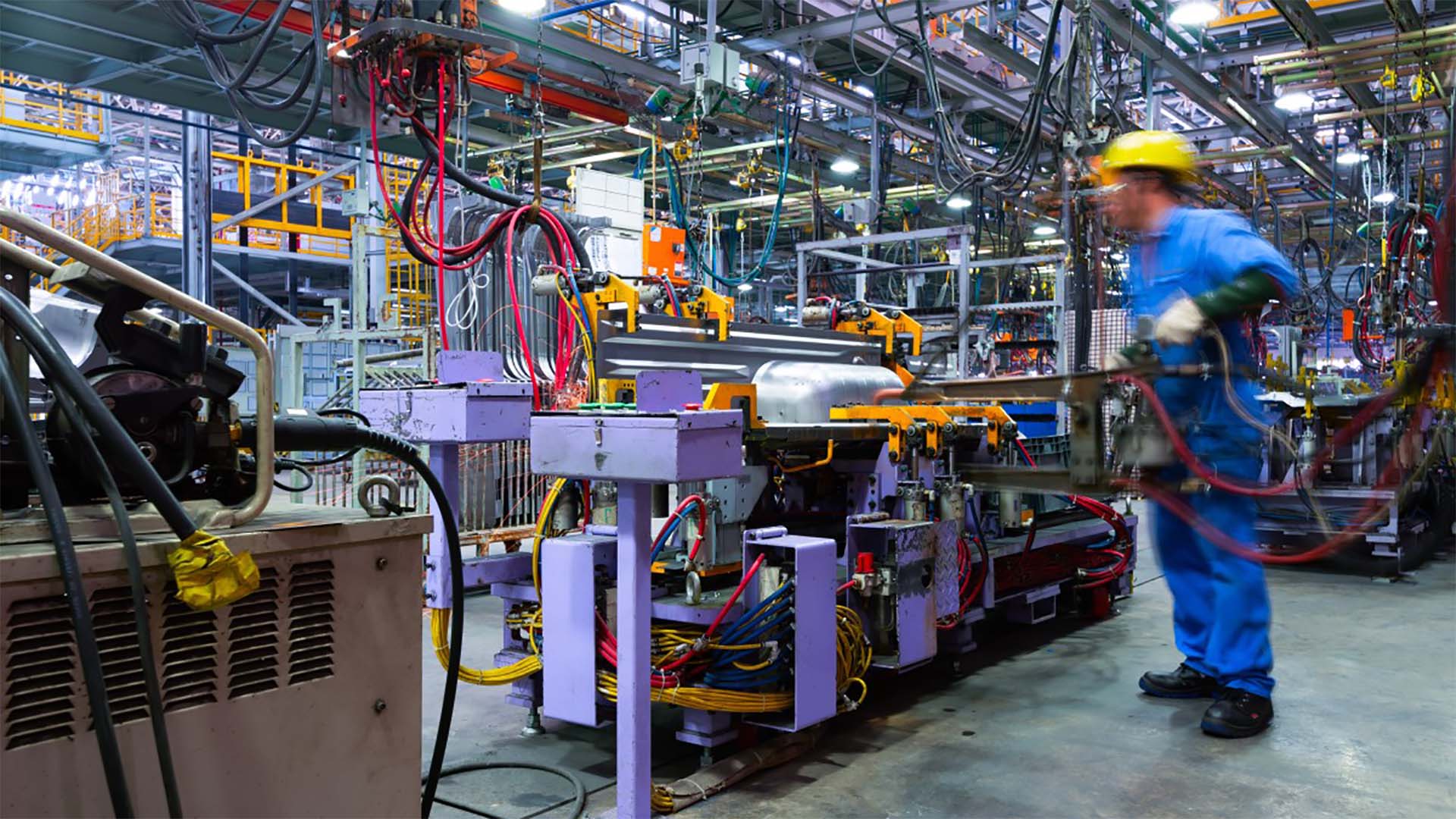 A worker preparing a machine for stamping metal parts