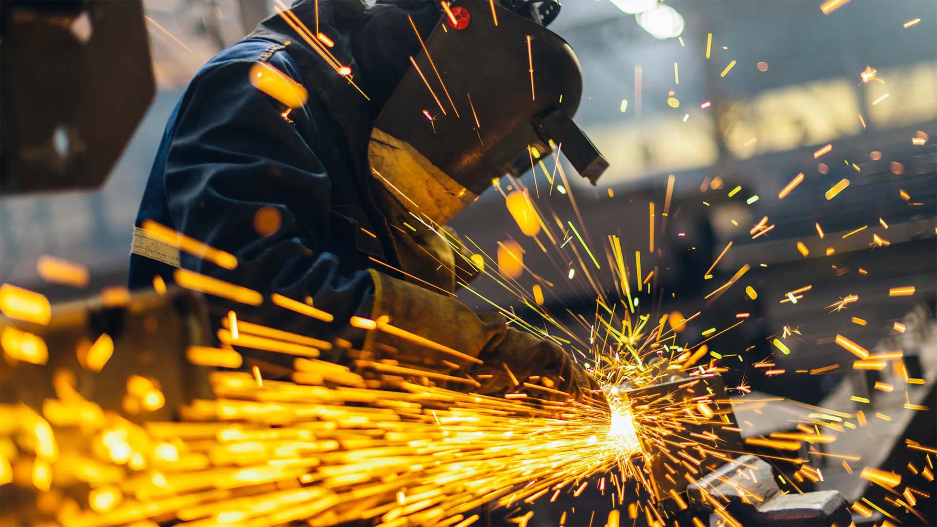 A worker grinding metal in a steel fabrication manufacturing plant