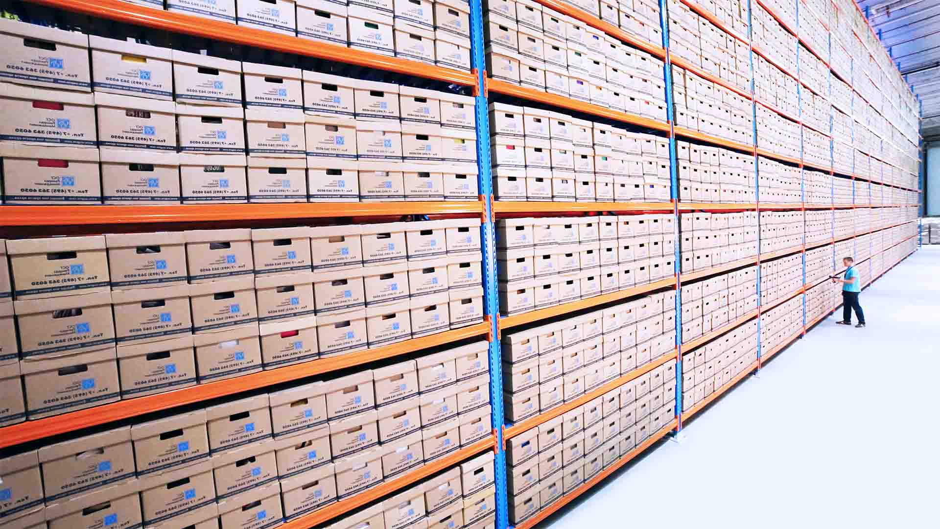 A warehouse worker next to a large rack of identical boxes