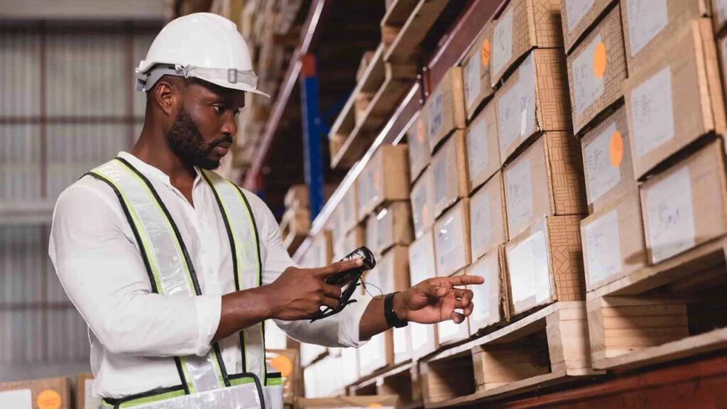A warehouse worker checking stock levels with a barcode scanner
