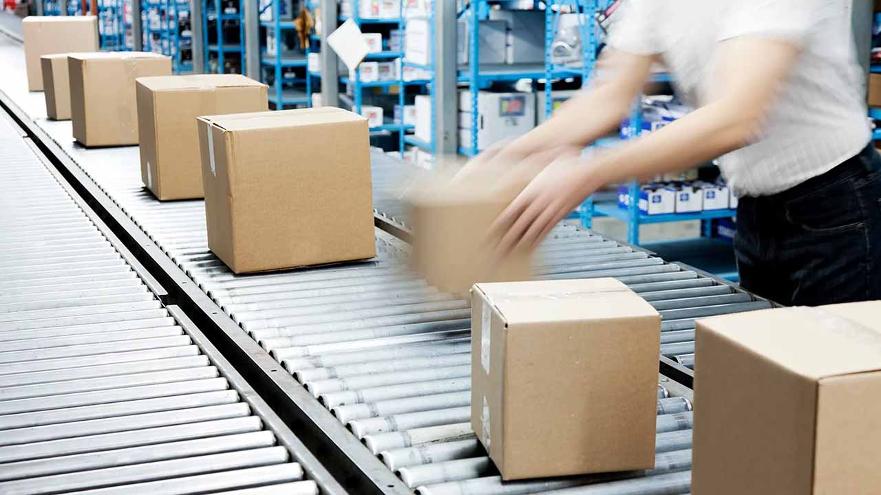 A warehouse worker case picking on a conveyor system