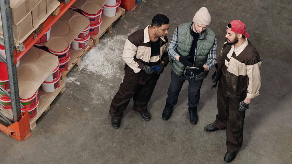 A group of warehouse workers checking inventory on a tablet device