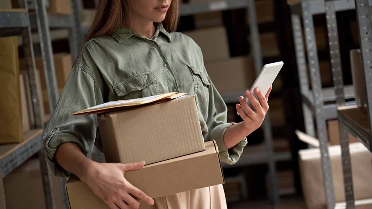 a woman checking an online order and holding boxes