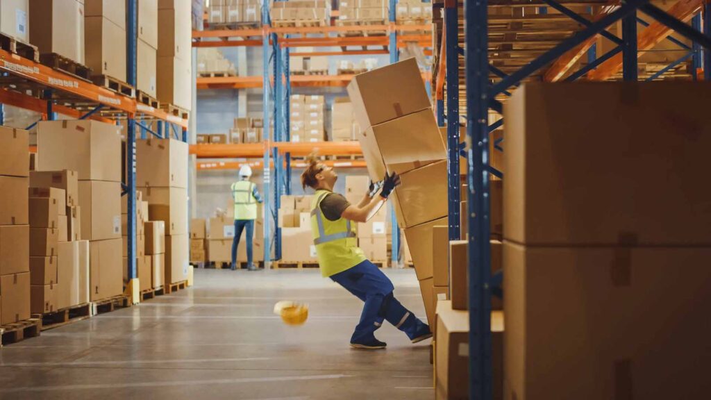 A warehouse worker getting injured from a poorly stacked pallet of cartons