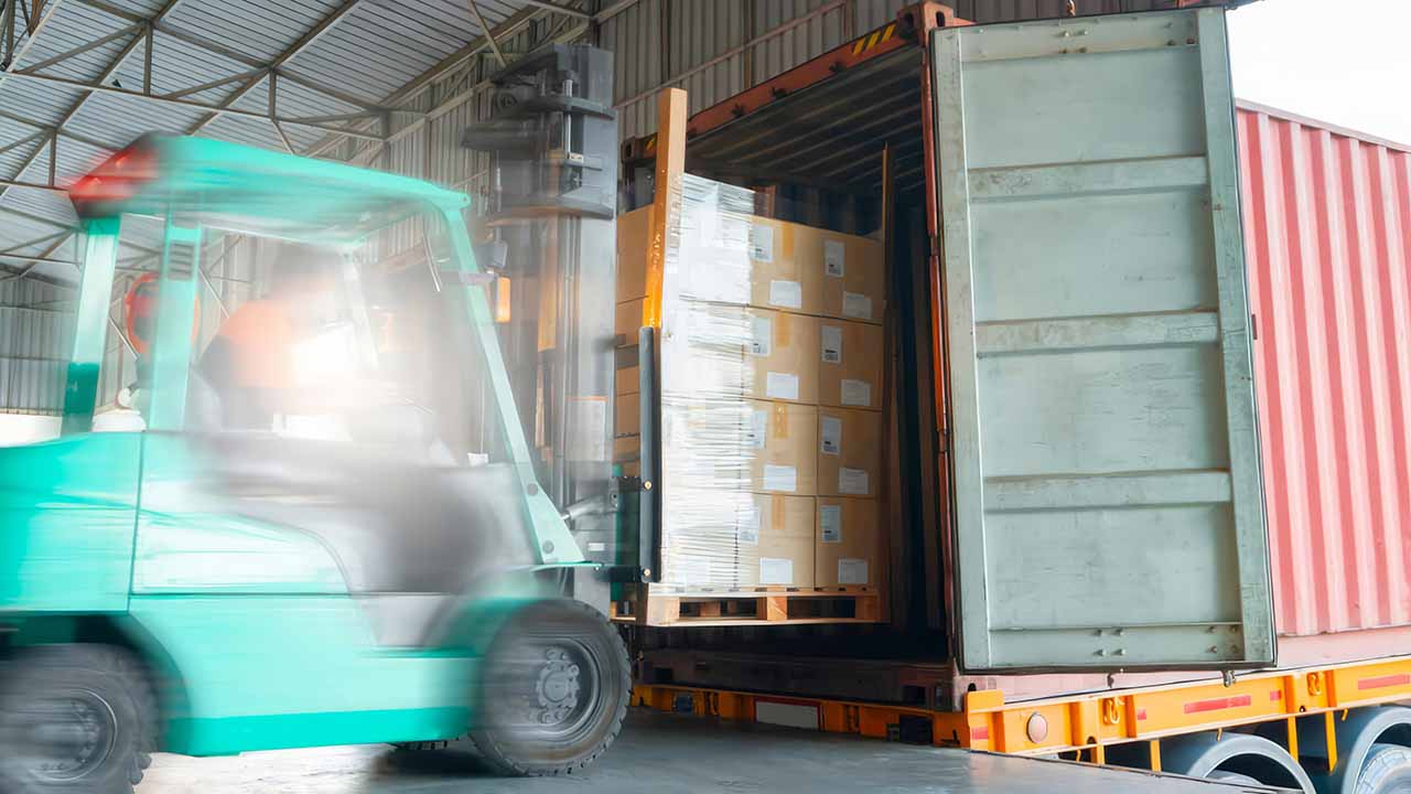 Container being unloaded from a truck at a warehouse